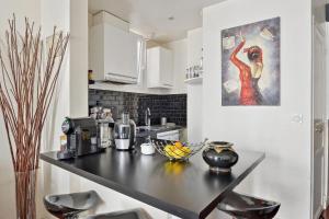 une cuisine avec un comptoir noir et un tableau mural dans l'établissement Charming apartment in Courbevoie - Welkeys, à Courbevoie
