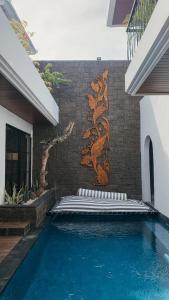 a swimming pool in front of a wall with a mural at The Wina Villa Canggu in Canggu