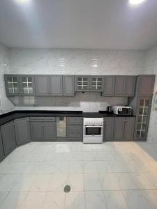 a kitchen with gray cabinets and a white tile floor at درة العروس شاليه شاطئ البرادايس in Durat  Alarous