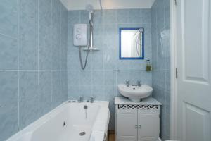 een blauw betegelde badkamer met een wastafel en een bad bij Contemporary 2 bed flat in Bristol, Free Parking in Bristol
