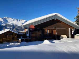 een blokhut in de sneeuw met bergen op de achtergrond bij Chalet Lalula in Rosswald