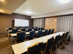 una sala conferenze con tavoli, sedie e lavagna bianca di ​Hotel Route-Inn Kumagaya​ a Kumagaya