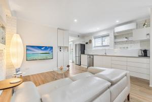 a living room with a white couch and a kitchen at Comfortable & Convenient Coastal Studio in Maroochydore