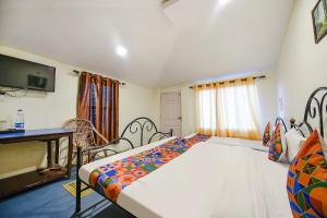 a bedroom with a bed and a desk and a television at FabExpress 180 Degree Resort in Mussoorie