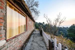 a brick building with a window and a fence at FabExpress 180 Degree Resort in Mussoorie