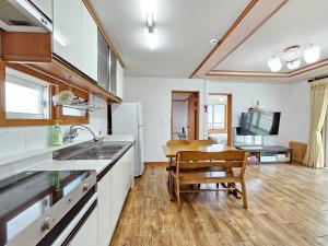 a kitchen with a sink and a dining room with a table at Seongsan Sunrise Pension in Seogwipo