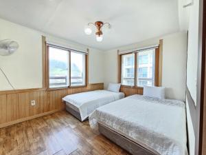 two beds in a room with two windows at Seongsan Sunrise Pension in Seogwipo