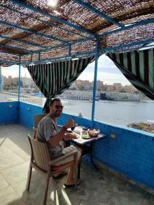 Un uomo seduto a un tavolo con un drink di Jamaica Guest House a Aswan