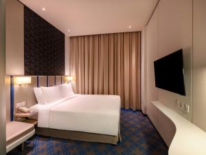 a hotel room with a white bed and a television at Holiday Inn Express Singapore Katong, an IHG Hotel in Singapore