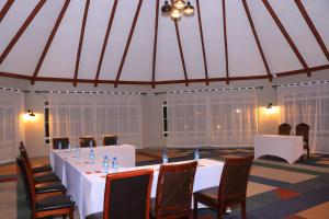 马查科斯Oldonyo Sapuk Resort的帐篷里的会议室，里面摆放着白色桌椅。