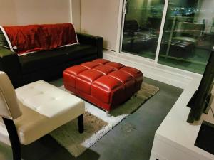a living room with a red leather ottoman and a chair at 1 Bedroom with Balcony in Calgary