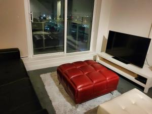 a red leather ottoman in a living room with a television at 1 Bedroom with Balcony in Calgary