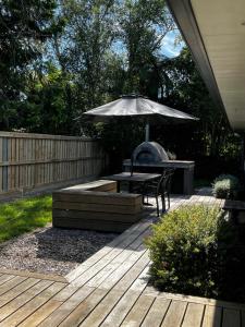 a wooden deck with a table and an umbrella at Walk to Town from this Modern and Warm Home in Central Cambridge Four Beds Available in Cambridge