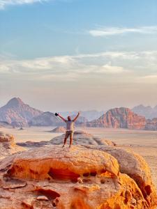 a man standing on top of a rock in the desert at Moon Rum Camp in Wadi Rum