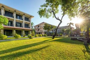 een park voor een gebouw met een boom bij HOI AN HISTORIC HOTEL in Hội An