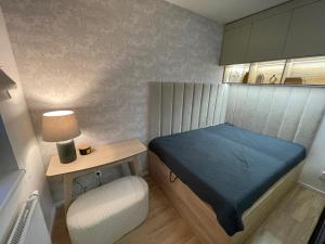 a small bedroom with a blue bed and a chair at Apartmán TOMI in Brezno