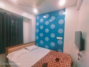 a bedroom with a bed and a blue wall at Amrit Guest House Pune in Pune