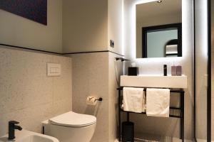 a bathroom with a toilet and a sink and a mirror at TRIBE Milano Malpensa in Vizzola Ticino