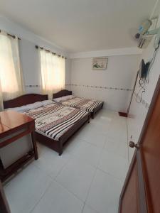 2 camas en una habitación con suelo de baldosa blanca en NHÀ NGHỈ NAM PHƯƠNG en Ha Tien