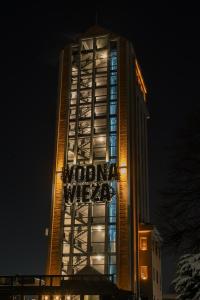 a tall building with a sign on it at night at 4 Strony Apartamenty w Wodnej Wieży in Pszczyna
