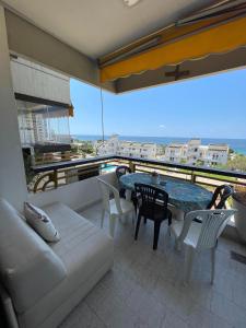 a balcony with a couch and a table and chairs at Chalet en urbanisazion de Solemar, piscinas, tennis, futbol, Balon cesto in Al Kaslīk