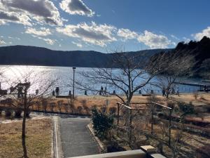 Lake Side Inn MIRAHAKONE في Moto-hakone: اطلالة على بحيرة فيها ناس تمشي على الشاطئ