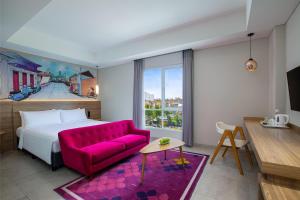 a bedroom with a large bed and a pink couch at favehotel Sidoarjo in Sidoarjo