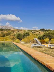 a swimming pool with blue water in front of a hill at Azienda Agricola Pietra Pizzuta in Torre deʼ Passeri