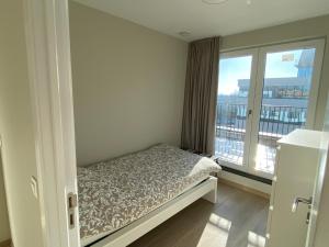 een kleine slaapkamer met een bed en een groot raam bij Residentie Sluispark in Gent