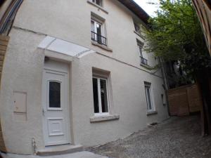 un edificio blanco con puerta y ventana en L'Atelier- appartement cosy avec cour - centre, en Bourgoin