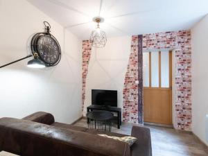 een woonkamer met een bank en een klok aan de muur bij L'Atelier- appartement cosy avec cour - centre in Bourgoin