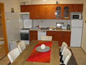 a small kitchen with a wooden table and chairs at Ezüsthíd Apartman in Balatongyörök