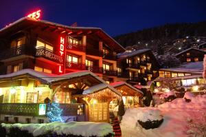 um alojamento de esqui na neve à noite em Hôtel Les Côtes, Résidence Loisirs et Chalets em Morzine