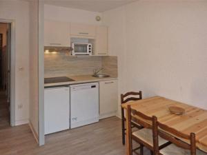 eine kleine Küche mit einem Holztisch sowie einem Tisch und Stühlen in der Unterkunft Résidence ORR DES FORETS - Studio pour 4 Personnes 794 in Les Orres