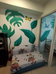 a bedroom with a bed with leaves and butterflies on the wall at SM Bicutan Condominium in Manila