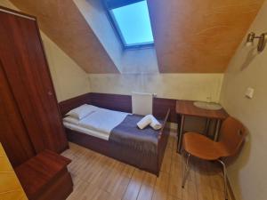 a small bedroom with a bed and a desk and a window at Motel Górno in Górno