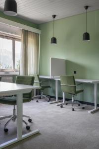 uma sala de conferências com cadeiras e mesas verdes e um quadro branco em Kloster by b-smart em Schaan