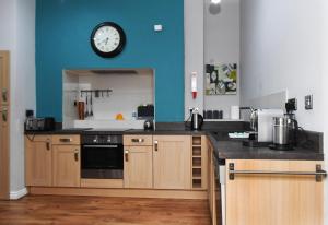 una cucina con orologio su una parete blu di Harrogate Self Catering - Harrogate Convention View Suite - Private Parking Spaces a Harrogate