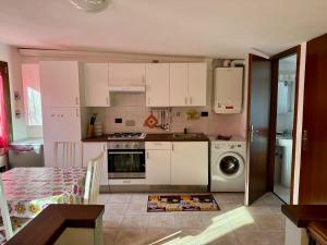 a kitchen with white cabinets and a washing machine at VIDI HOME in Vidiciatico