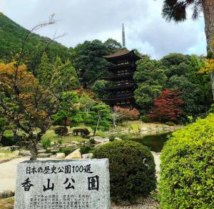 a stone sign in front of a garden with a pagoda at KAMENOI HOTEL Setouchi Hikari in Hikari