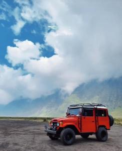 a red jeep parked on a dirt road at Bromo Holiday Guest House in Ngadisari