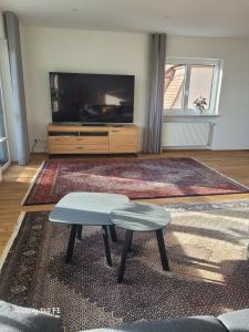 a living room with a table and a tv at Modernes Ferienappartement An der Steige in Wilhermsdorf
