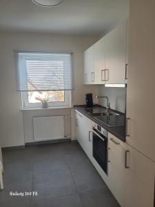 a kitchen with white cabinets and a sink and a window at Modernes Ferienappartement An der Steige in Wilhermsdorf