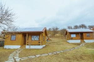 a log cabin with a solar roof on a field at Country Garden - Országkert in Păuleni-Ciuc