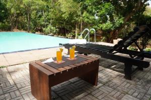 丹布勒的住宿－Star Dambulla，一张木桌,旁边是游泳池,上面有饮料