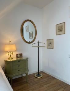 a bedroom with a green dresser with a lamp and a mirror at Hotel Berg in Stuttgart
