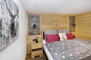 ein Schlafzimmer mit einem Bett mit einer Holzwand in der Unterkunft Chalet Claudia in Bartholomäberg