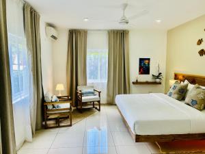 a bedroom with a bed and a chair and a window at The Seaboards Apartments Seychelles in Mahe
