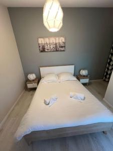 1 dormitorio con 1 cama blanca y 2 toallas en Le Paris Eiffel - Appartement Cosy en plein centre, en Bourgoin