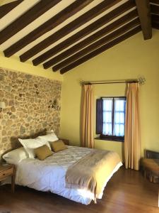 1 dormitorio con cama y pared de piedra en Casa Rural Trebol4Hojas en San Pedro